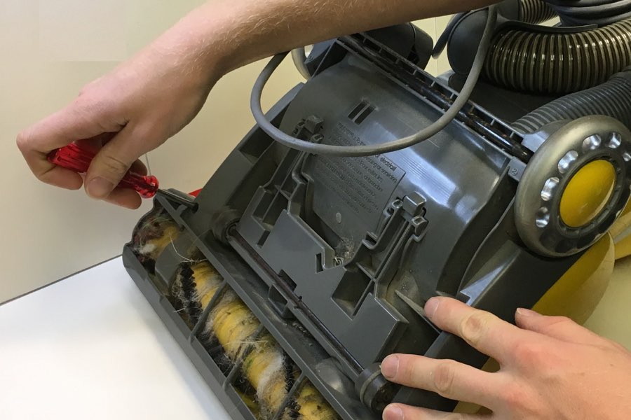 More Than Vacuums tech repairing an upright vacuum